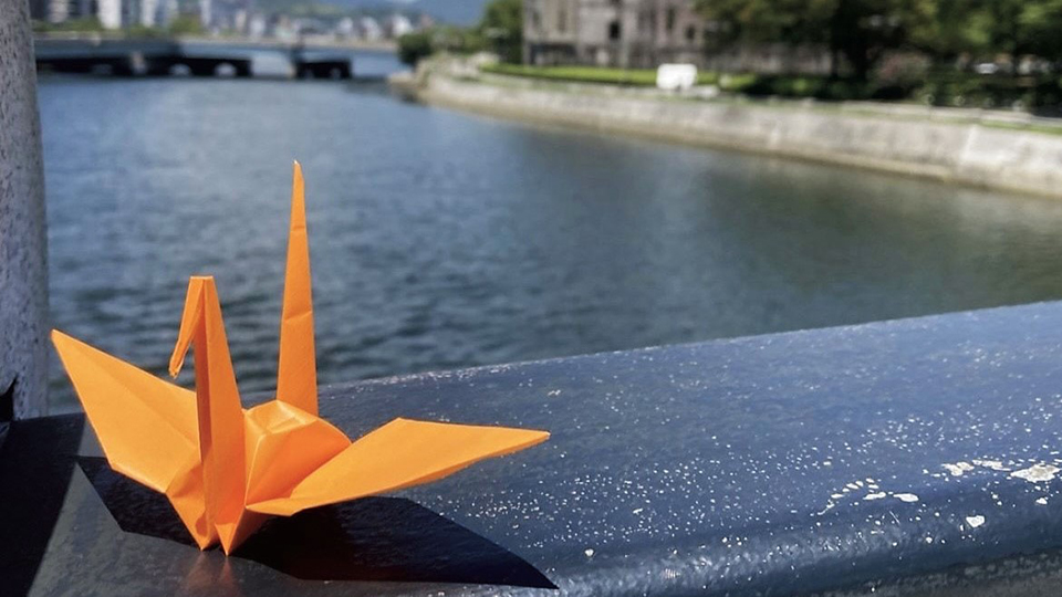 元安川をバックにしたオレンジの折り鶴