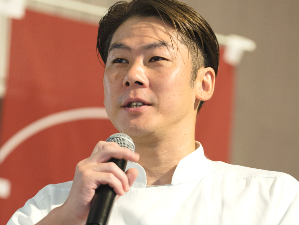 マイクを持って演説をする男性の写真