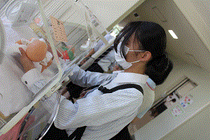 保育器で高校生が体重1000ｇのベビー人形の重さをかみしめている。