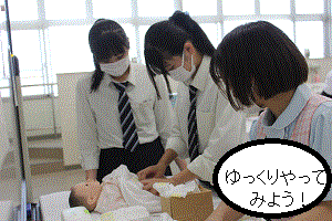 高校生に学生が赤ちゃんにおむつ交換の方法を伝えている｡