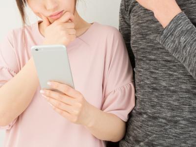 スマートフォンを見て考える男女