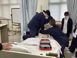 胸骨圧迫をしながらＡＥＤの装着をしている