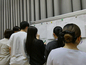 学生数名がホワイトボードに向かい記入している。